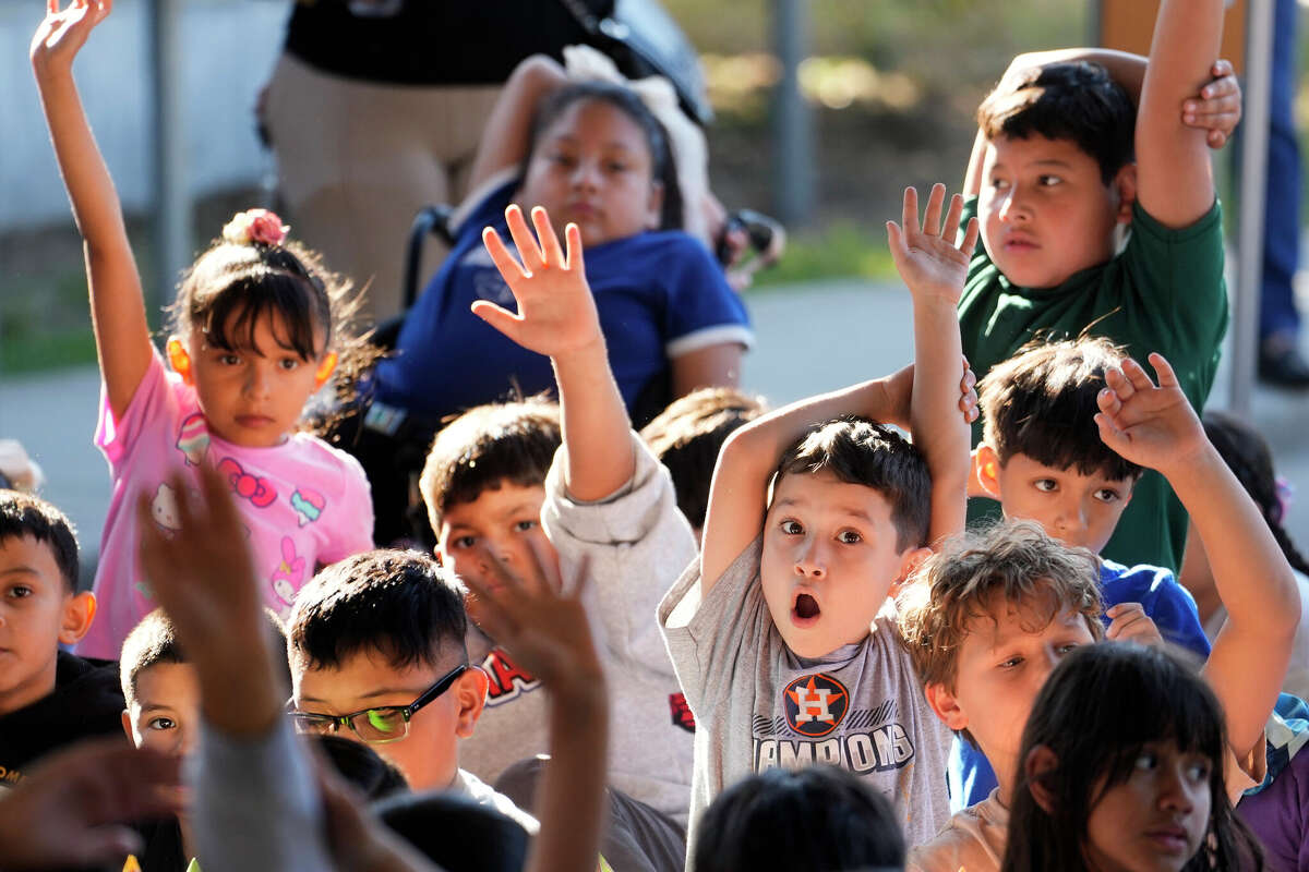 Alex Andre 8, right, and other third graders at Herrera Elementary School raise their hands to ask questions of Mike Foreman, retired astronaut, during his presentation before a launch of rockets made from plastic bottles in Houston Thursday, Oct. 9, 2025. The rockets powered by baking soda and vinegar were launched during the Arm & Hammer Baking Soda Rocket Day a nationwide initiative designed to spark curiosity and creativity in STEAM.