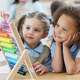 Happy preschool friends enjoy using an abacus during preschool. The students are wearing school uniforms.