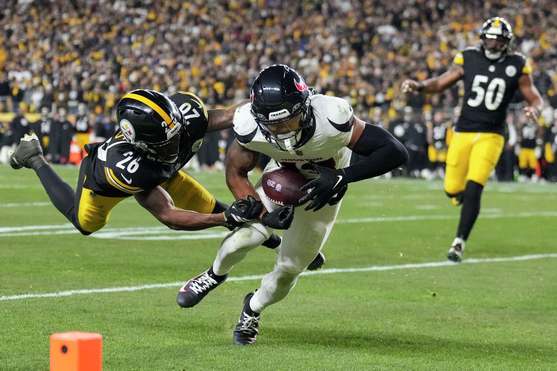 Houston Texans wide receiver Christian Kirk (13) gets past a tackle by Pittsburgh Steelers cornerback Brandin Echols (26) for a 6-yard touchdown during the first half of an NFL wild-card playoff football game in Pittsburgh, Monday, Jan. 12, 2026.