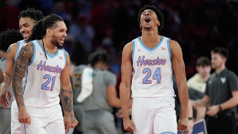 Houston's Chase McCarty (24) and Emanuel Sharp (21) celebrate during a timeout in the second half of an NCAA college basketball game against West Virginia Tuesday, Jan. 13, 2026, in Houston. (AP Photo/David J. Phillip)