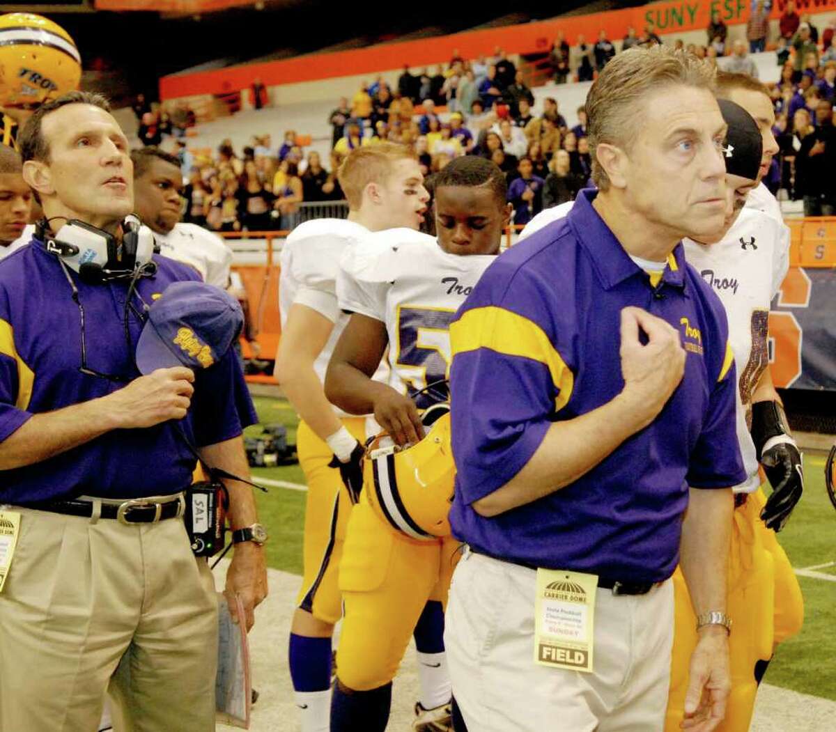 High school football -- Troy coach Jack Burger, right, blesses himself at the conclusion of the Nation Anthem before the Class AA state championship game. (Luanne M. Ferris / Times Union)