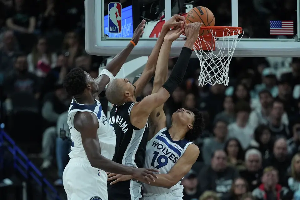 San Antonio Spurs forward Victor Wembanyama, center, scores against Minnesota Timberwolves guard Anthony Edwards, left, and forward Joan Beringer (19) during the second half of an NBA basketball game in San Antonio, Saturday, Jan. 17, 2026.