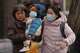 Women carry a toddler across a street in Beijing, Monday, Jan. 19, 2026.