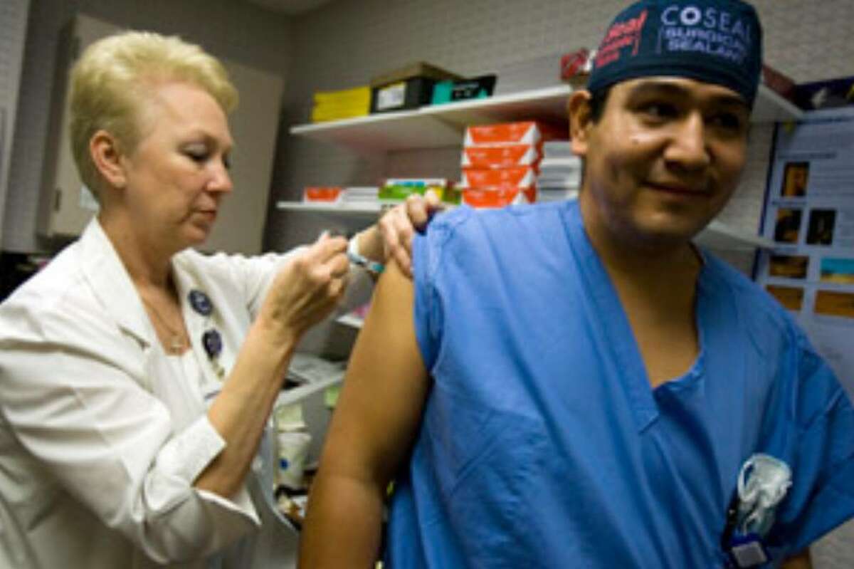 Employee health nurse Fran McLaughlin administers a flu shot to surgical first assistant Eduardo Farias at Methodist Specialty and Transplant Hospital.