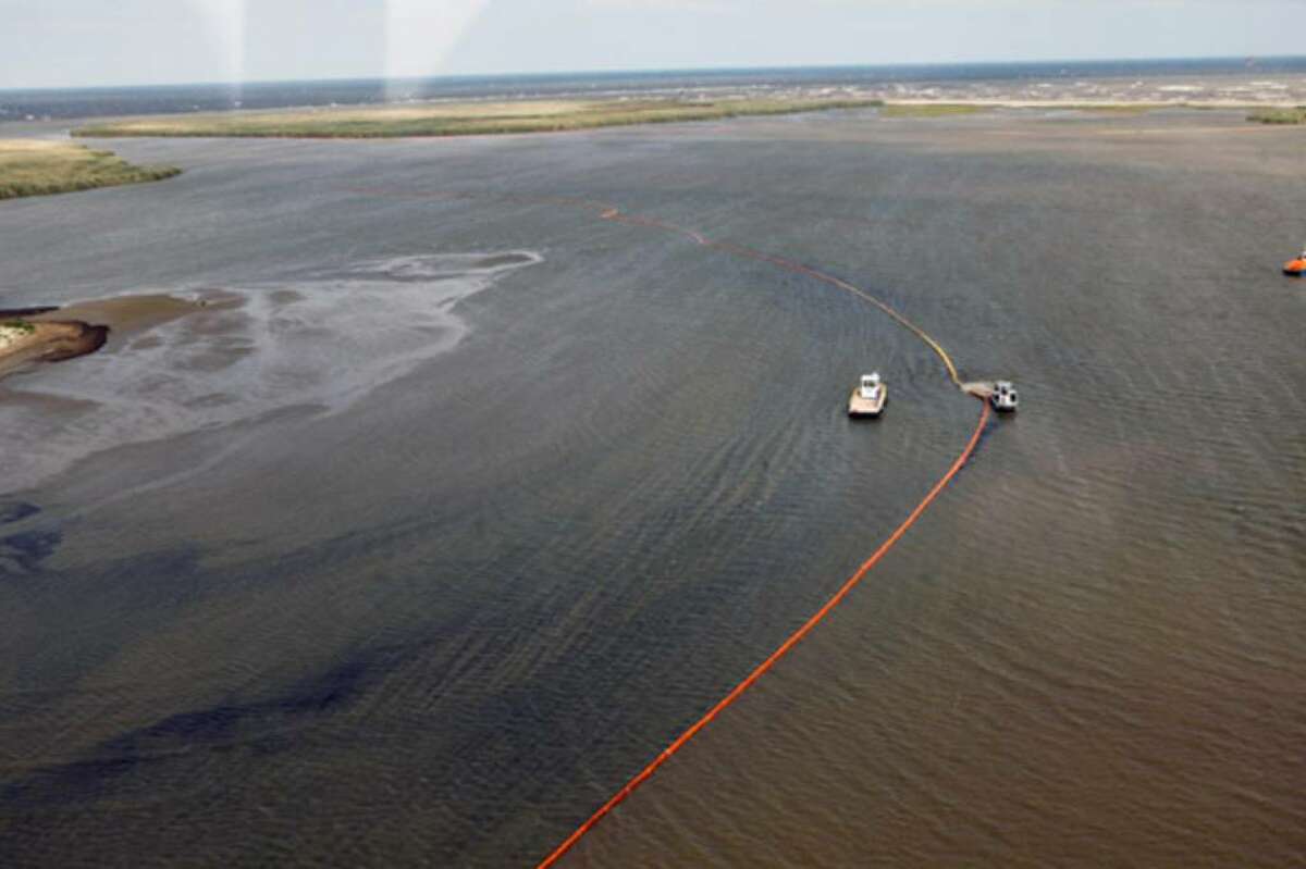 Workers place oil booms near the coast in Louisiana. Gov. Bobby Jindal said that least 10 wildlife areas are in the oil plume's path.