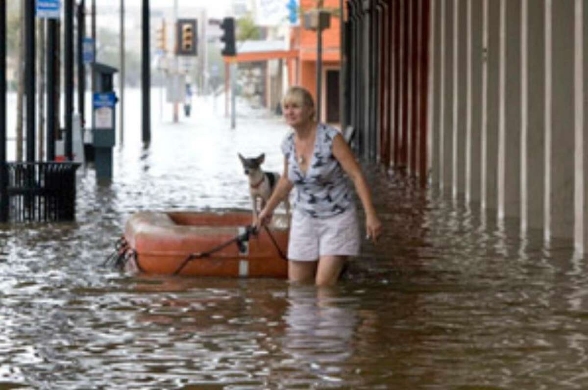 THEN: Leslie Sundell floats her dog, Scooby, on a life raft as she makes her way along the Strand last year in the aftermath of Hurricane Ike in Galveston.
