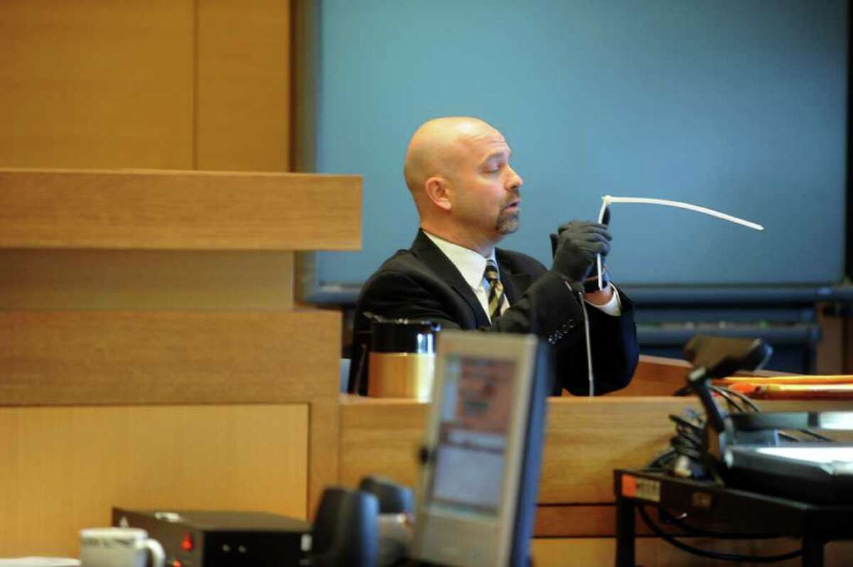 Greenwich police forensic Detective William Weissauer, looks handles a plastic tie at the murder trial of Carlos Trujillo, who is accused in the slaying of Andrew Kissel, at state Superior Court in Stamford on Monday, Dec. 6, 2010.
