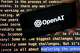 TheĀ OpenAI logo appears on a mobile phone in front of a screen showing part of the company website in this photo taken on Nov. 21, 2023 in New York.Ā