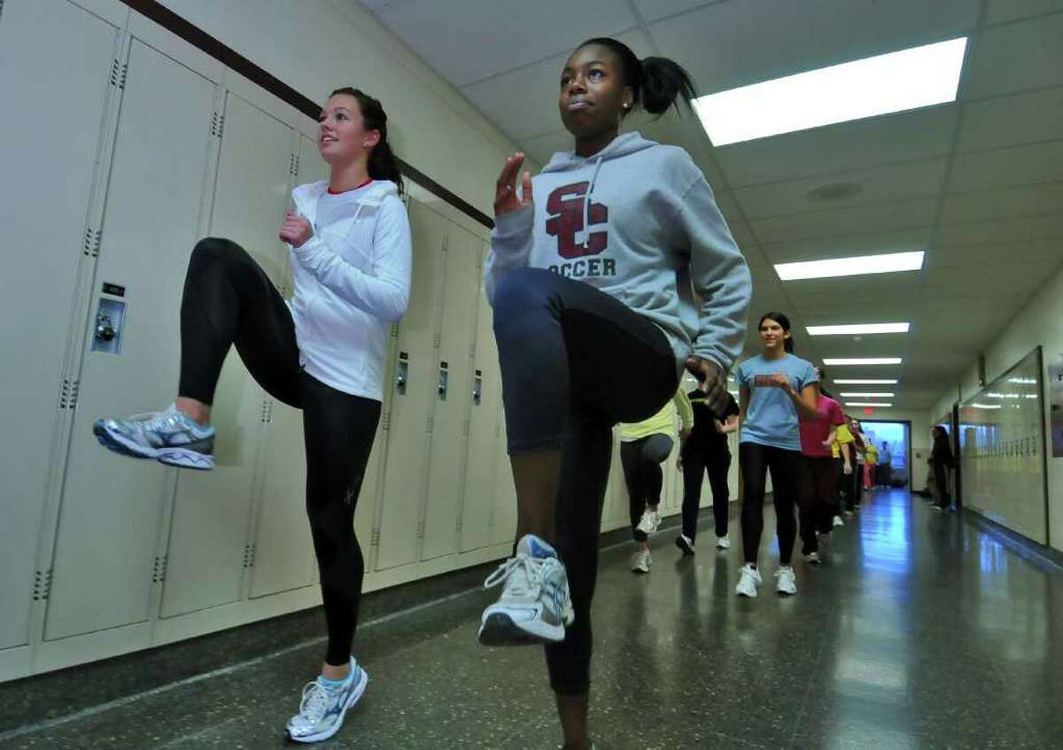 High school track -- Colonie sprinters Kristina Lenge, left, and Uwa Omorogee warm up during practice in the school's hallways. (Philip Kamrass / Times Union )