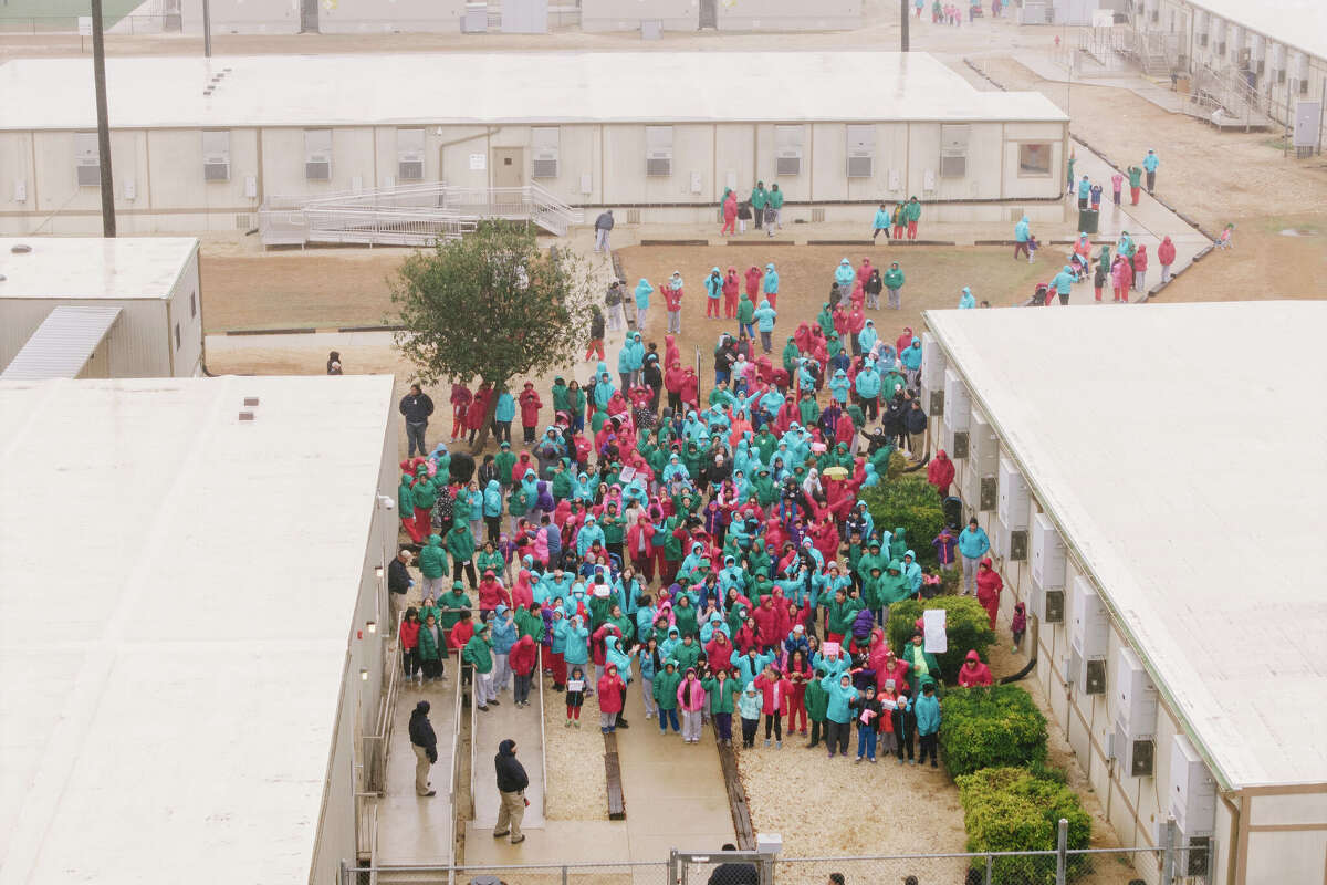 Detainees held at the South Texas Family Residential Center wave signs during a demonstration in Dilley, Texas, Saturday, Jan. 24, 2026. (AP Photo/Brenda Baza´n)