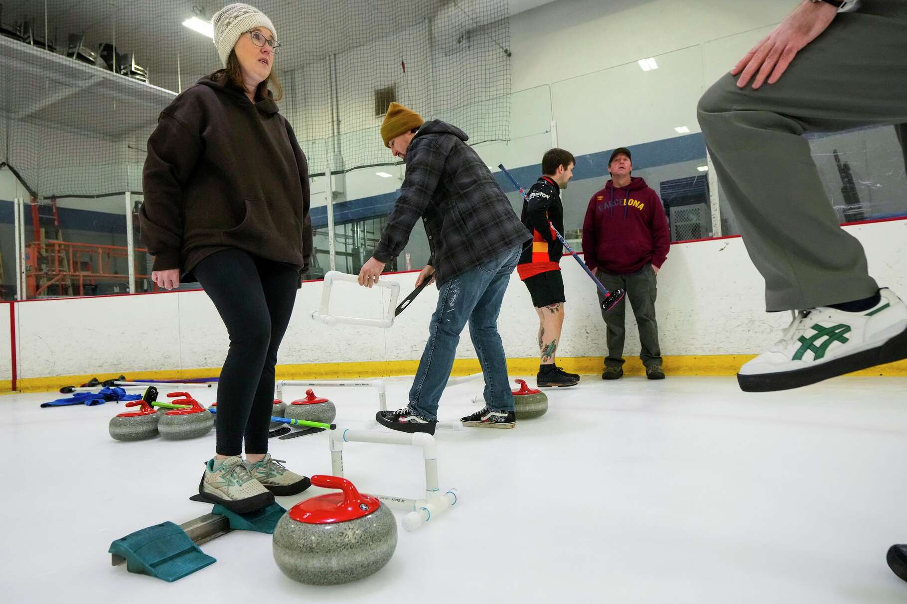 Jennifer Maynard, left, listens to instructions as she takes a Learn-to-Curl class at Bellerive Ice Center in Houston, Sunday, Feb. 1, 2026. The Curling Club of Houston offers Learn-to-Curl classes for all ages and groups. The 2-hour Curling Experience includes on-ice instructions on how to deliver a curling stone, sweep, and strategize, and ending with a mini-game of curling.