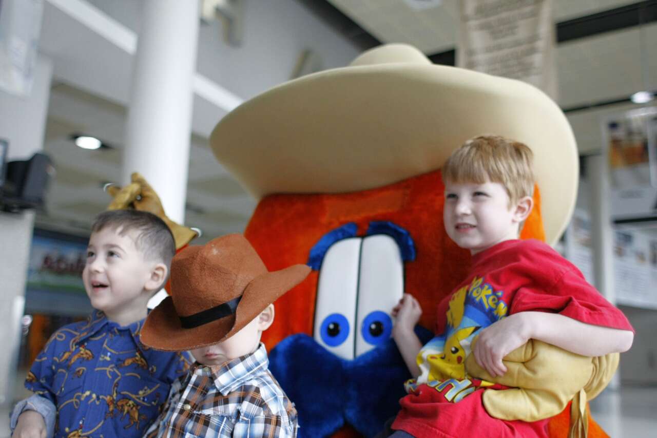 Kyle Bjornson of Philadelphia, center, puts his cowboy hat over his eyes as he, his brother Mitchell Bjornson left, and friend Matthew Onufrow pose for a picture with Howdy the Houston Livestock Show and Rodeo's mascot. 