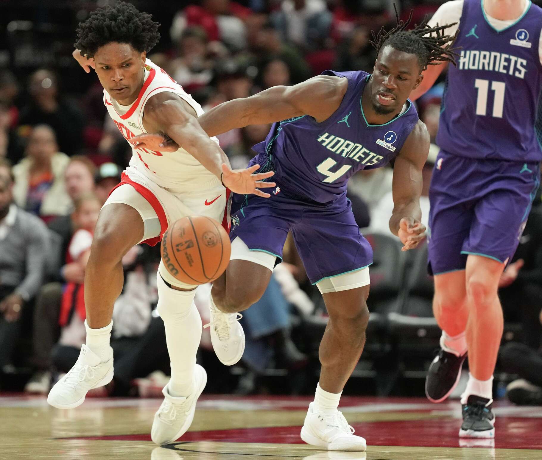 Houston Rockets guard Amen Thompson (1) and Charlotte Hornets guard Sion James (4) chase after a loose ball in the fist half of game action at the Toyota Center in Houston on Thursday, Feb. 5, 2026.