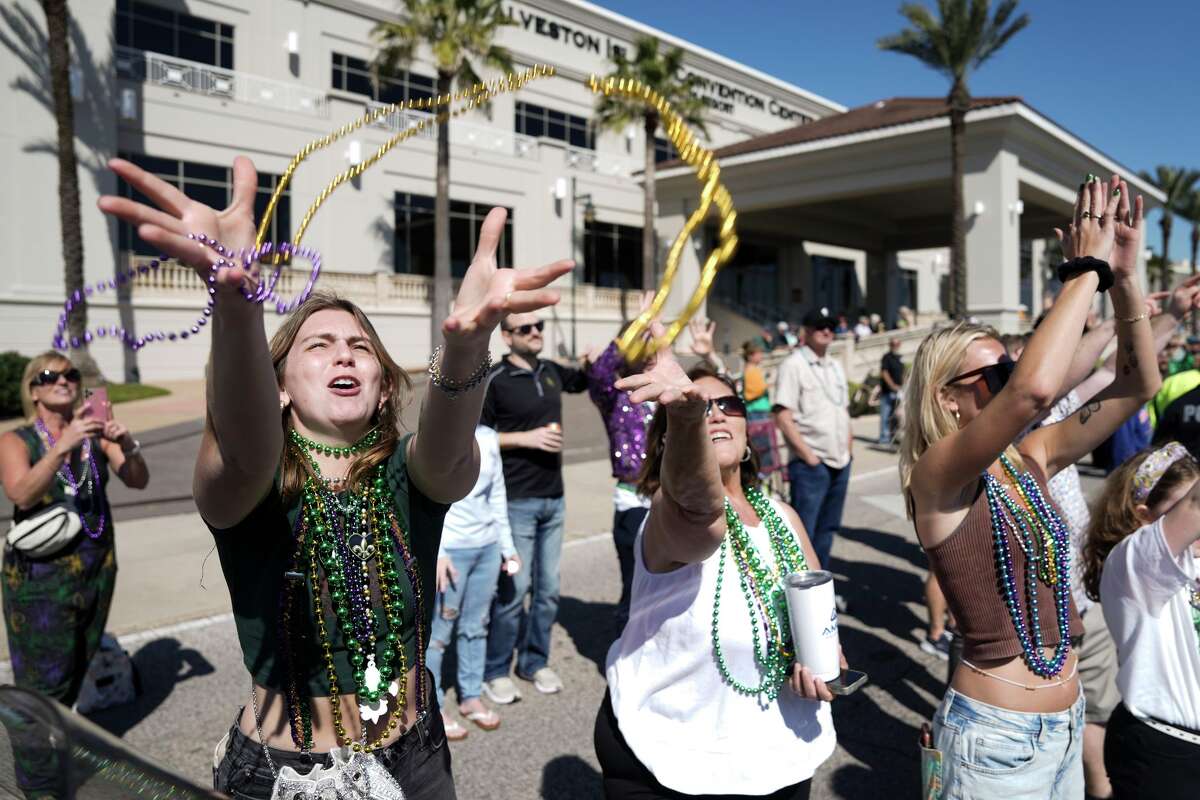 Izzy Kent catches beads thrown to her from a float during the Krewe of Aquarius Parade in celebration of Mardi Gras, Saturday, Feb. 7, 2026, in Galveston.