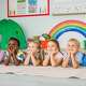 Group of happy little children are sitting on the floor in the kindergarten.