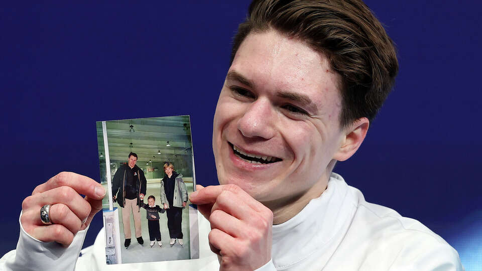 Max Nauumov of Team United States reacts while holding a picture of his family after competing in the mens' figure skating short program.