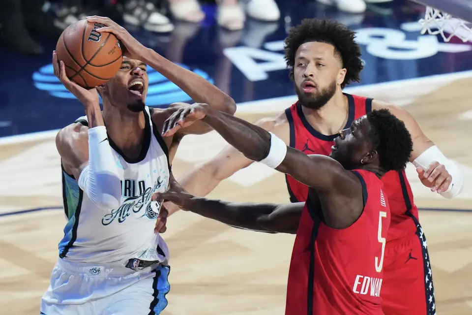 World center Victor Wembanyama, of France, is defended by USA Stars guard Cade Cunningham and guard Anthony Edwards during the NBA All-Star basketball game Sunday, Feb. 15, 2026, in Inglewood, Calif. (AP Photo/Jae C. Hong)