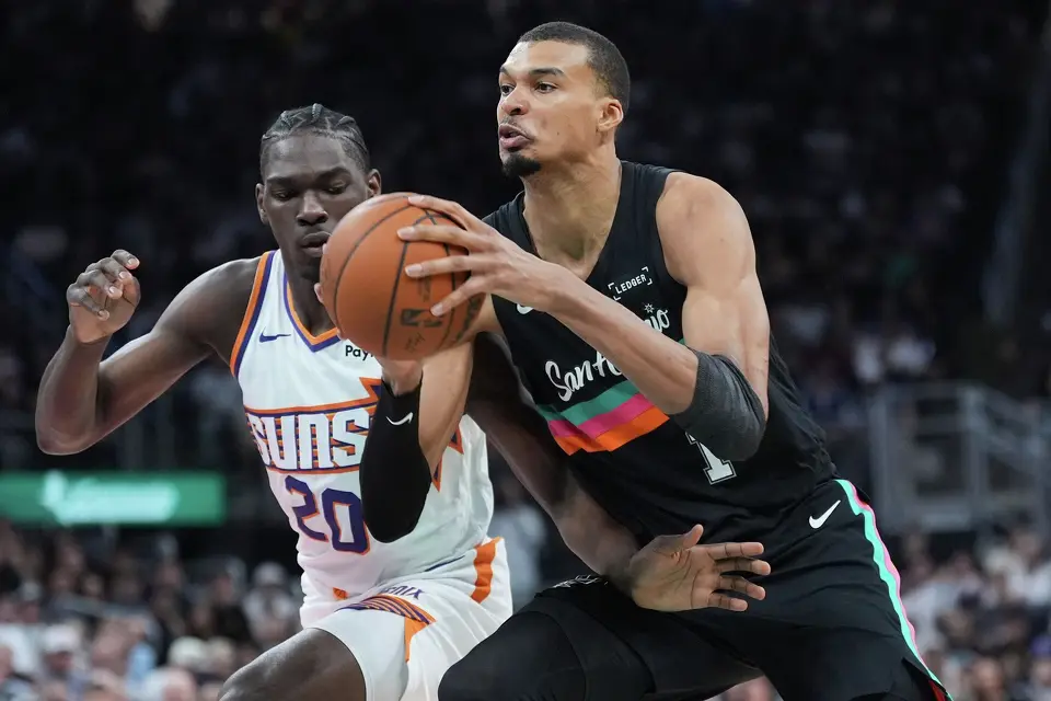 El francés Victor Wembanyama, de los Spurs de San Antonio, avanza junto a Rasheer Fleming, de los Suns de Phoenix, en el encuentro del jueves 19 de febrero de 2026 (AP Foto/Eric Gay)