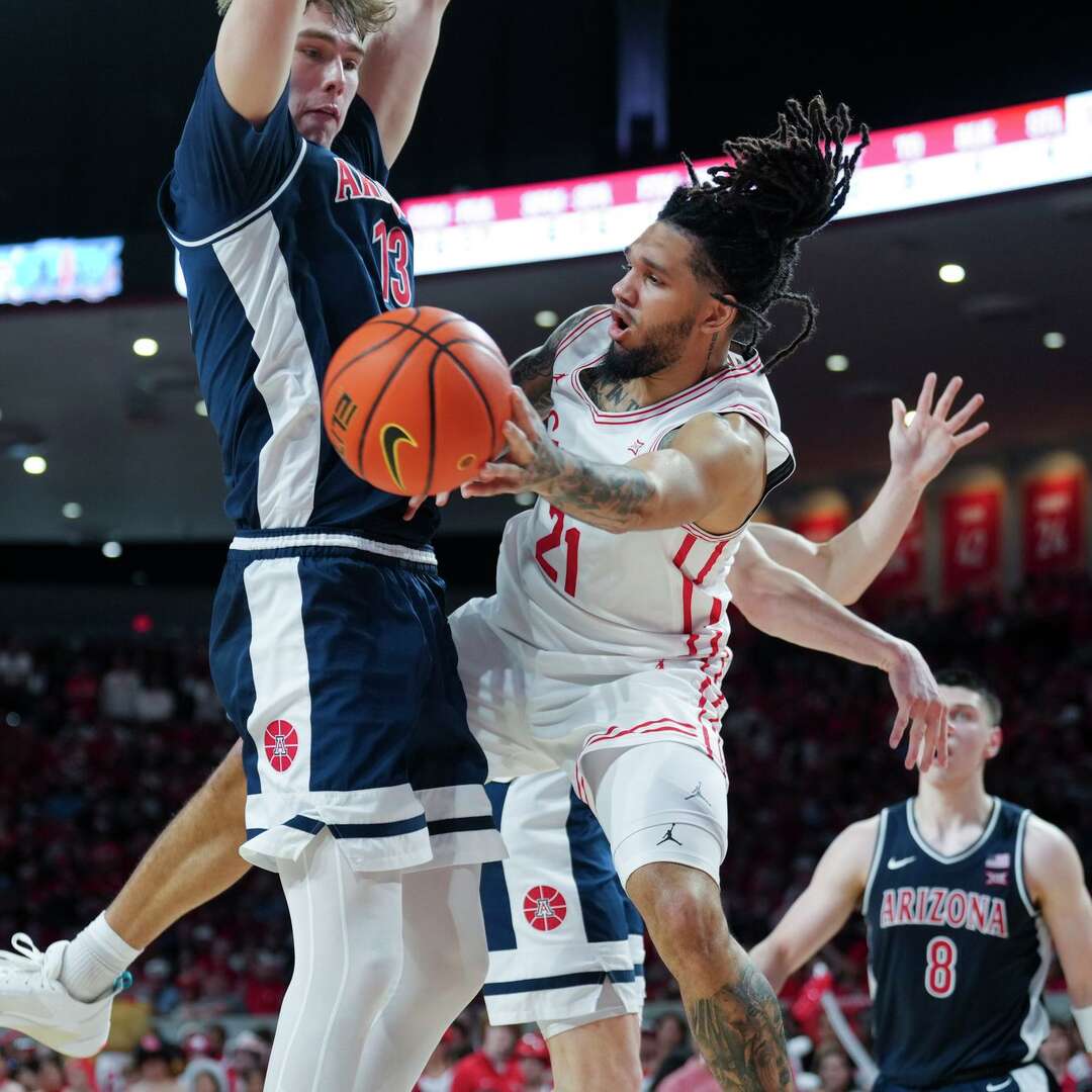 Houston guard Emanuel Sharp (21) tries to pass around Arizona center Motiejus Krivas (13) during the second half of an NCAA college basketball game in Houston, Saturday, Feb. 21, 2026.