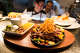 A steak fajita skillet topped with fried onion strings is one of the dishes offered by father-and-son chefs Julian and Beto Rodarte at their Beto and Son restaurant in Trinity Groves.