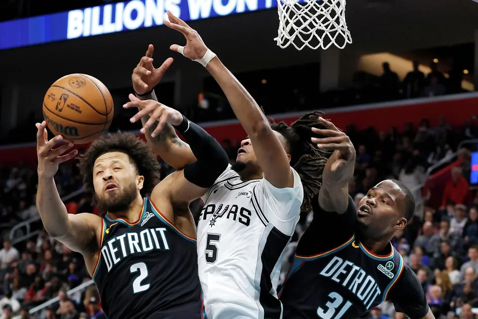 Detroit Pistons guard Cade Cunningham (2) battles San Antonio Spurs guard Stephon Castle (5) for a rebound with Pistons guard Javonte Green (31) helping on the play during the first half of an NBA basketball game Monday, Feb. 23, 2026, in Detroit.