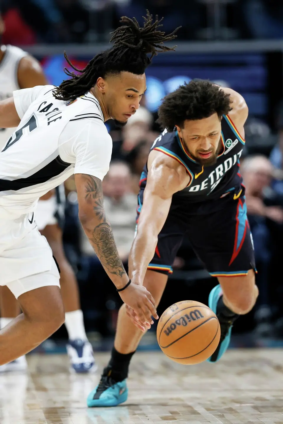 San Antonio Spurs guard Stephon Castle (5) and Detroit Pistons guard Cade Cunningham, right, scramble for the ball during the first half of an NBA basketball game Monday, Feb. 23, 2026, in Detroit. (AP Photo/Duane Burleson)