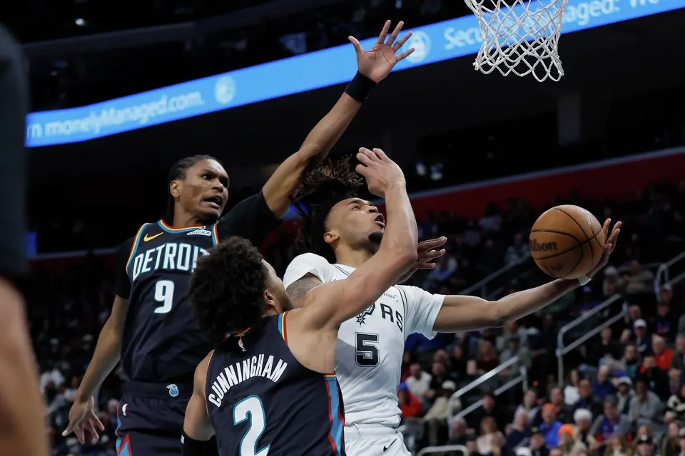 Stephon Castle (5), de los Spurs de San Antonio, se alza hacia la canasta frente a Ausar Thompson (9) y Cade Cunningham (2), de los Pistons de Detroit, durante la primera mitad del juego de baloncesto de la NBA del lunes 23 de febrero de 2026, en Detroit. (AP Foto/Duane Burleson)