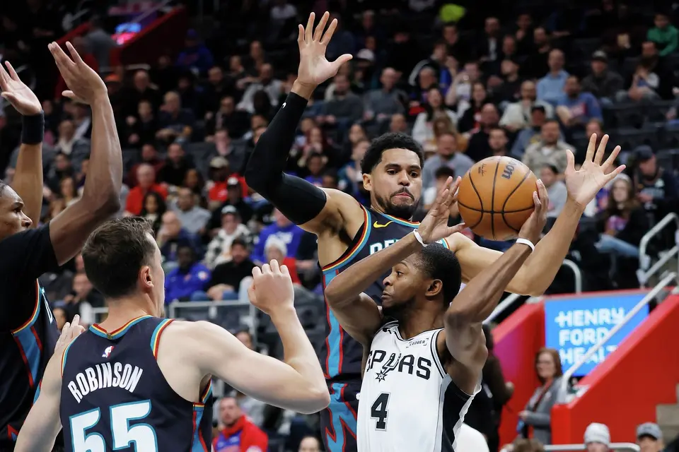 San Antonio Spurs guard De'aaron Fox (4) looks to pass the ball against Detroit Pistons forward Tobias Harris, top right, and forward Duncan Robinson, front left, during the first half of an NBA basketball game Monday, Feb. 23, 2026, in Detroit. (AP Photo/Duane Burleson)
