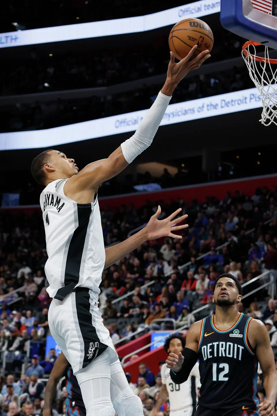 San Antonio Spurs forward Victor Wembanyama, left, goes to the basket against the Detroit Pistons during the first half of an NBA basketball game Monday, Feb. 23, 2026, in Detroit. (AP Photo/Duane Burleson)