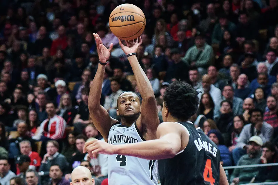 San Antonio Spurs' De'Aaron Fox (left) lines up a shot over Toronto Raptors' Scottie Barnes (4) during the second half of an NBA basketball game in Toronto, Wednesday, Feb. 25, 2026. (Sammy Kogan/The Canadian Press via AP)