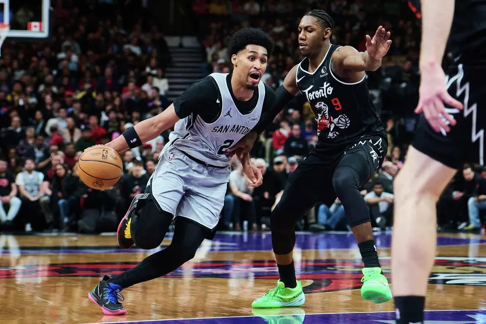 San Antonio Spurs' Dylan Harper (2) drives past Toronto Raptors' RJ Barrett (9) during the second half of an NBA basketball game in Toronto, Wednesday, Feb. 25, 2026. (Sammy Kogan/The Canadian Press via AP)