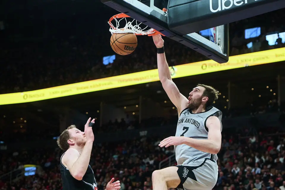 San Antonio Spurs' Luke Kornet (7) dunks on Toronto Raptors' Jakob Poeltl (19) during the second half of an NBA basketball game in Toronto, Wednesday, Feb. 25, 2026. (Sammy Kogan/The Canadian Press via AP)