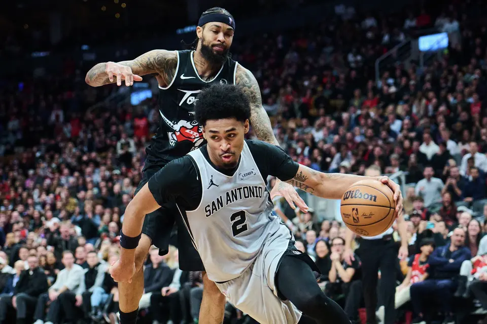 San Antonio Spurs' Dylan Harper (2) drives past Toronto Raptors' Brandon Ingram (3) during the second half of an NBA basketball game in Toronto, Wednesday, Feb. 25, 2026. (Sammy Kogan/The Canadian Press via AP)