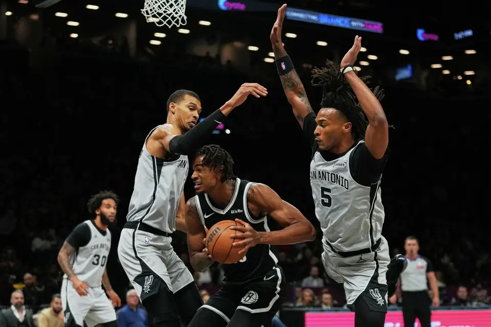 San Antonio Spurs' Victor Wembanyama, left, and Stephon Castle, right, defends Brooklyn Nets' Nic Claxton during the first half of an NBA basketball game Thursday, Feb. 26, 2026, in New York. (AP Photo/Frank Franklin II)