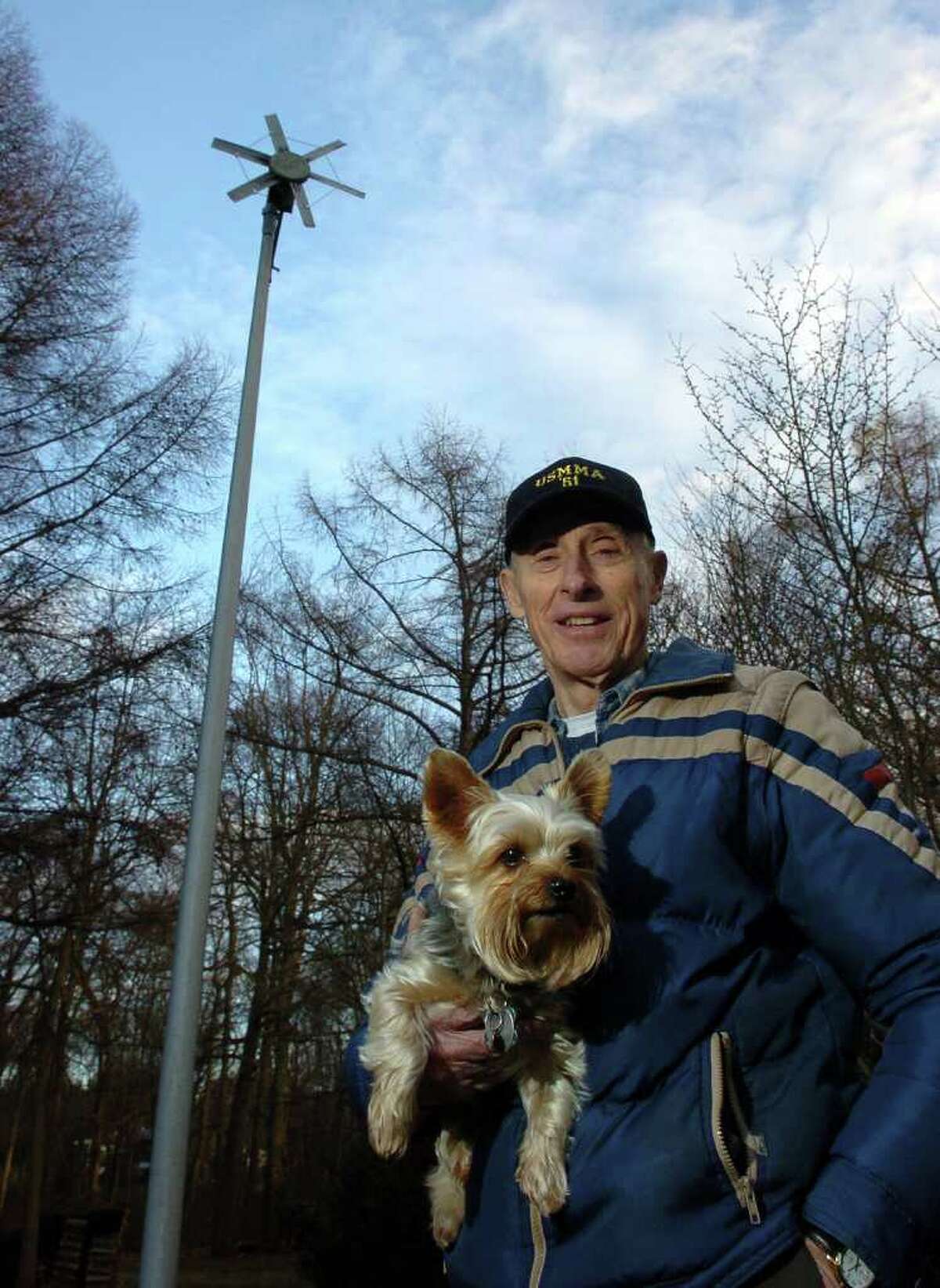 Henry D. Rotman poses with his dog Harley Davidson, behind his house in Milford, Conn. on Tuesday December 7, 2010, in front of the small wind turbine he constructed to generate electric power in 1985. Rotman sucessfully used the power to charge a series of gel batteries used for a diving project. As a former UI engineer, he doubts wind power will work well in Connecticut, due to the unpredictability of the wind here and its lack of sustained strength.