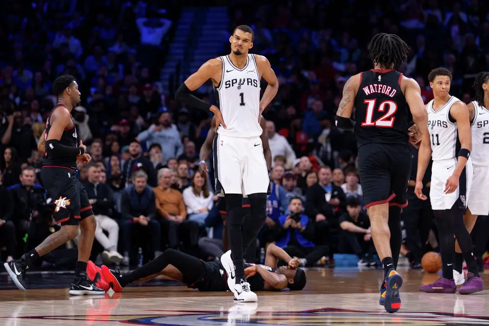 San Antonio Spurs' Victor Wembanyama, center, reacts to the foul by Carter Bryant, right, on Philadelphia 76ers' VJ Edgecombe, center floor, during the first half of an NBA basketball game, Tuesday, March 3, 2026, in Philadelphia. (AP Photo/Chris Szagola)