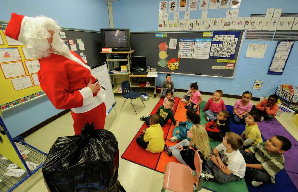 "Santa," played by Greg Vernon, with members of the Pi Kappa Alpha fraternity from RPI take gifts to the students of Troy's Public School 2 on December 13, 2010. (Skip Dickstein / Times Union)