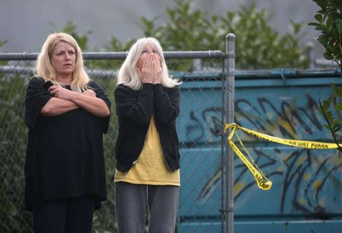 Trudie Overby, left, and her mother, Lee Stanley, watch events unfold on Sunday near the scene where four Lakewood Police officers were killed as they sat in a coffee shop near McChord Air Force Base. The women live in an apartment building next to the scene. | Photo gallery