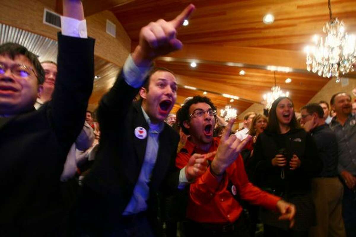 Sam Christensen and Faraz Zarghami react to R-71's lead in early returns at a party at the Edgewater Hotel in Seattle.