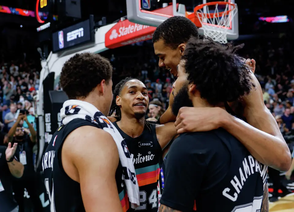 San Antonio Spurs guard Devin Vassell (24) talks to his teammates Carter Bryant (11), Victor Wembanyama (1) and Julian Champagnie (30) following their dramatic comeback victory over the LA Clippers at Frost Bank Center in San Antonio, Friday, March 6, 2026. The Spurs overcame a 25-point deficit to win the game 116-112.