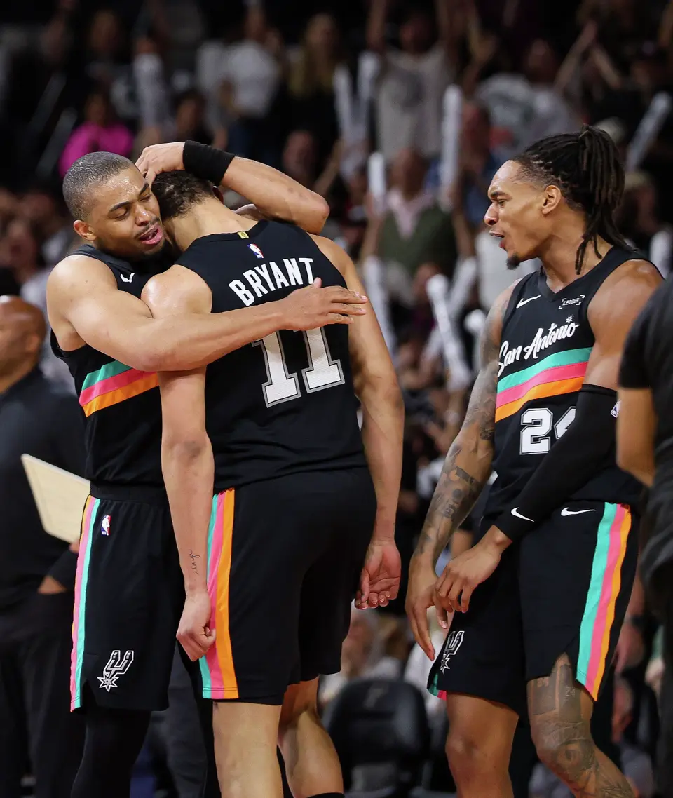 San Antonio Spurs’ Keldon Johnson (3) embraces Carter Bryant (11) as Devin Vassell (24) cheers beside them while celebrating Bryant’s fourth quarter dunk on the LA Clippers at Frost Bank Center in San Antonio, Friday, March 6, 2026.The Spurs rallied from a 25-point deficit to defeat the Clippers, winning the game 116-112.