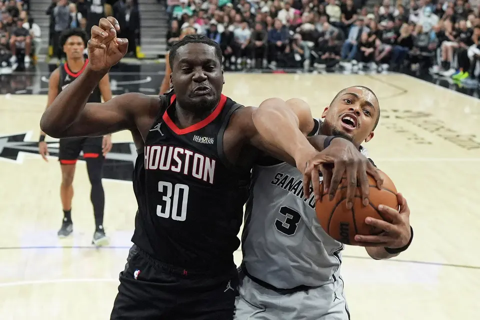 Houston Rockets center Clint Capela (30) and San Antonio Spurs forward Keldon Johnson (3) battle for a rebound during the first half of an NBA basketball game in San Antonio, Sunday, March 8, 2026. (AP Photo/Eric Gay)