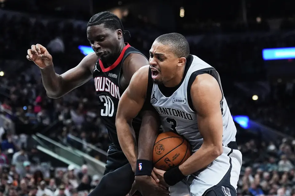 Houston Rockets center Clint Capela (30) and San Antonio Spurs forward Keldon Johnson (3) battle for a rebound during the first half of an NBA basketball game in San Antonio, Sunday, March 8, 2026. (AP Photo/Eric Gay)