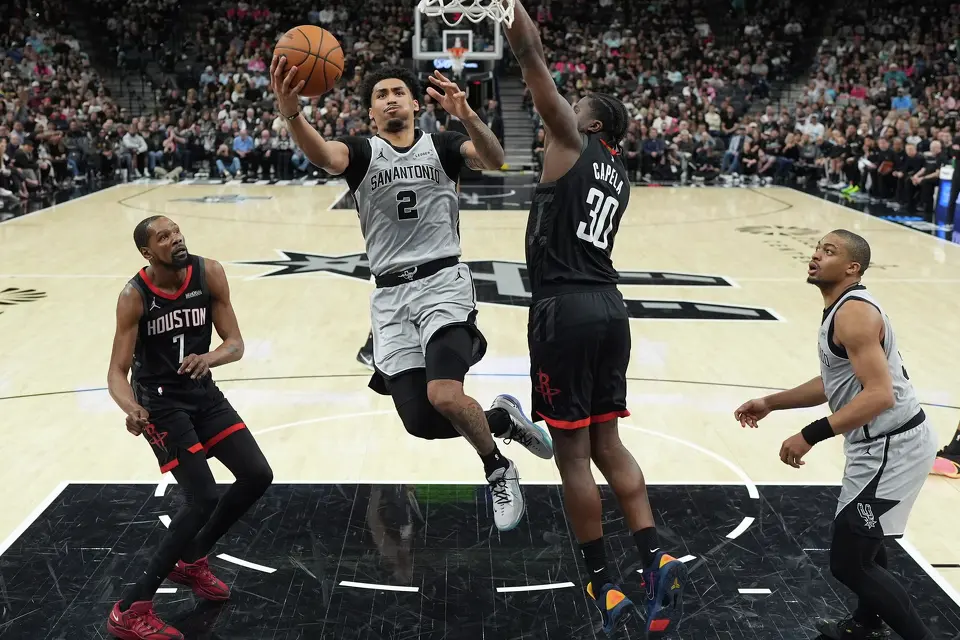 San Antonio Spurs guard Dylan Harper (2) drives to the basket against Houston Rockets center Clint Capela (30) during the first half of an NBA basketball game in San Antonio, Sunday, March 8, 2026. (AP Photo/Eric Gay)