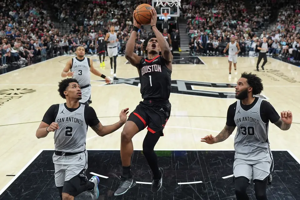 Houston Rockets guard Amen Thompson (1) drives to the basket between San Antonio Spurs guard Dylan Harper (2) and forward Julian Champagnie (30) during the second half of an NBA basketball game in San Antonio, Sunday, March 8, 2026. (AP Photo/Eric Gay)