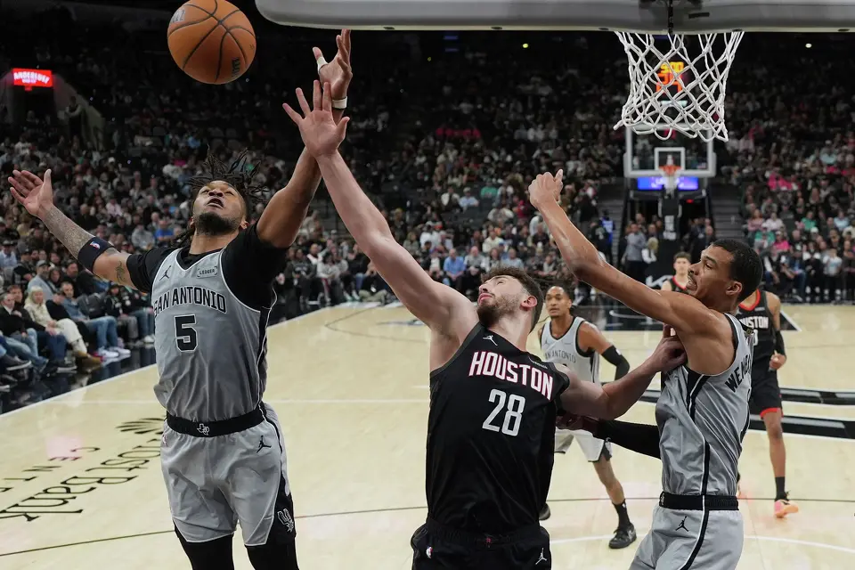 Houston Rockets center Alperen Sengun (28) drives to the basket against San Antonio Spurs guard Stephon Castle (5) and forward Victor Wembanyama (1) during the second half of an NBA basketball game in San Antonio, Sunday, March 8, 2026. (AP Photo/Eric Gay)