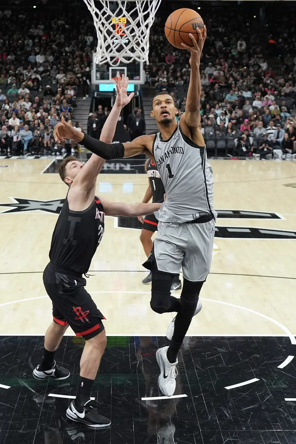 San Antonio Spurs forward Victor Wembanyama (1) drives to the basket past Houston Rockets center Alperen Sengun (28) during the first half of an NBA basketball game in San Antonio, Sunday, March 8, 2026. (AP Photo/Eric Gay)