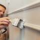 Man painting new decorative DIY wainscot panel at a wall in his house.