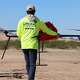 A member of a survey crew holding a drone in the dessert. Drone as a Service (DaaS) brings land accessibility to surveyors.