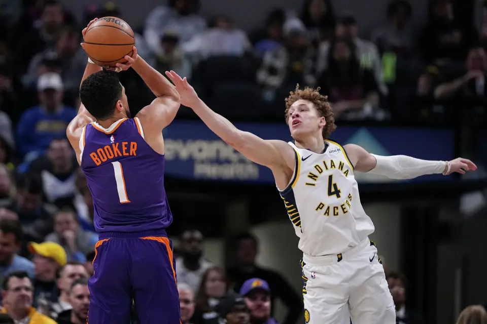 Phoenix Suns guard Devin Booker (1) shoots over Indiana Pacers guard Taelon Peter (4) during the first half of an NBA basketball game in Indianapolis, Thursday, March 12, 2026.